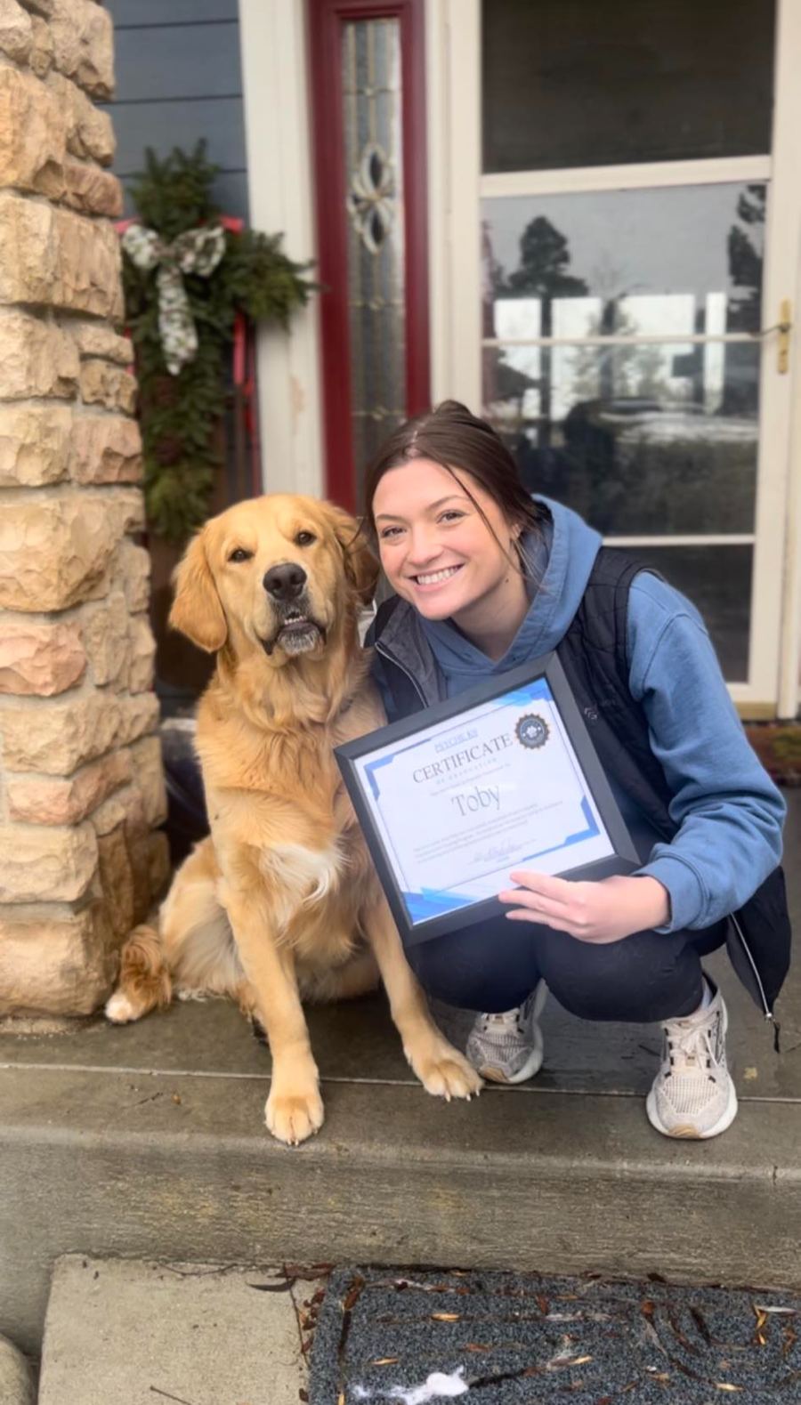 A proud client with her Golden Retriever and graduation certificate