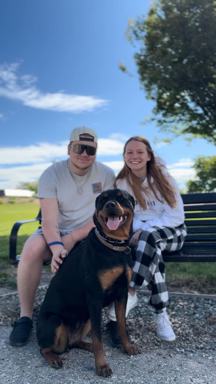 A happy couple sitting with their Rottweiler